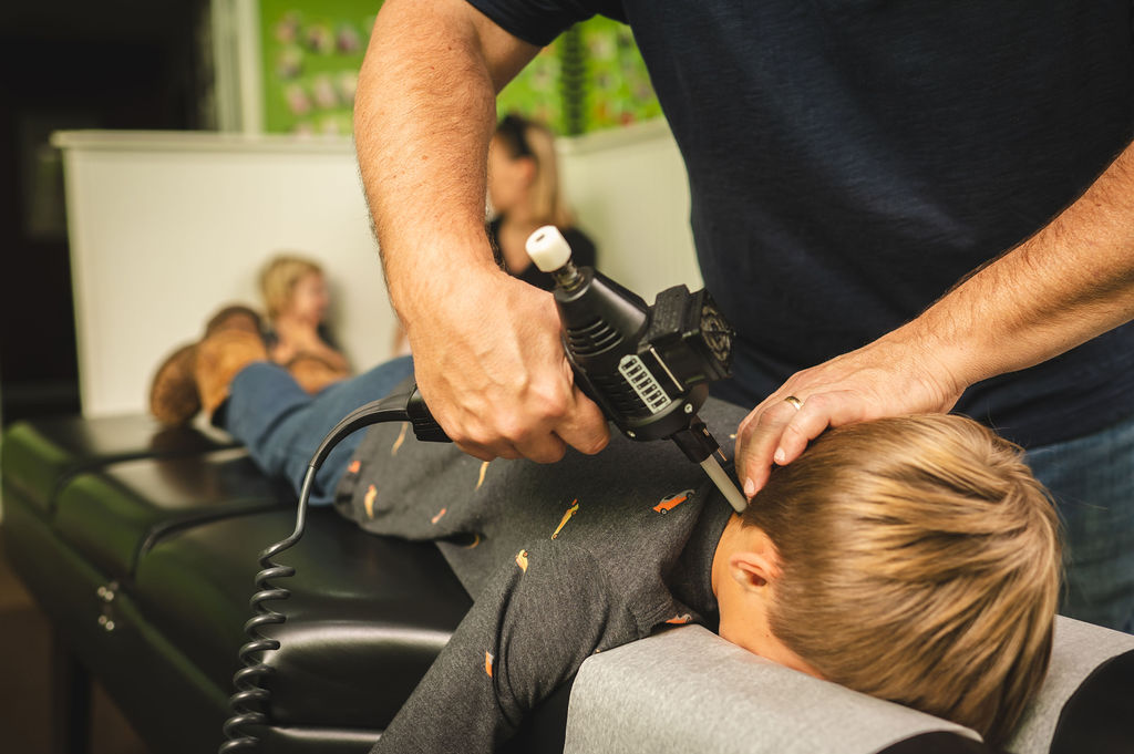 Dr. Mike Geran performing a gentle instrument-based chiropractic adjustment on a child at Foothills Chiropractic in Travelers Rest, SC